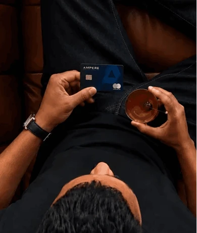 A man holding an Ampere card and a drink